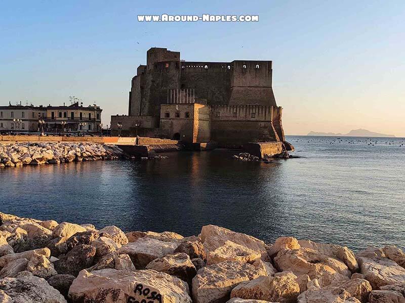 Egg Castle (Castel dell'Ovo) in Naples seen from the waterfront rocks at sunset